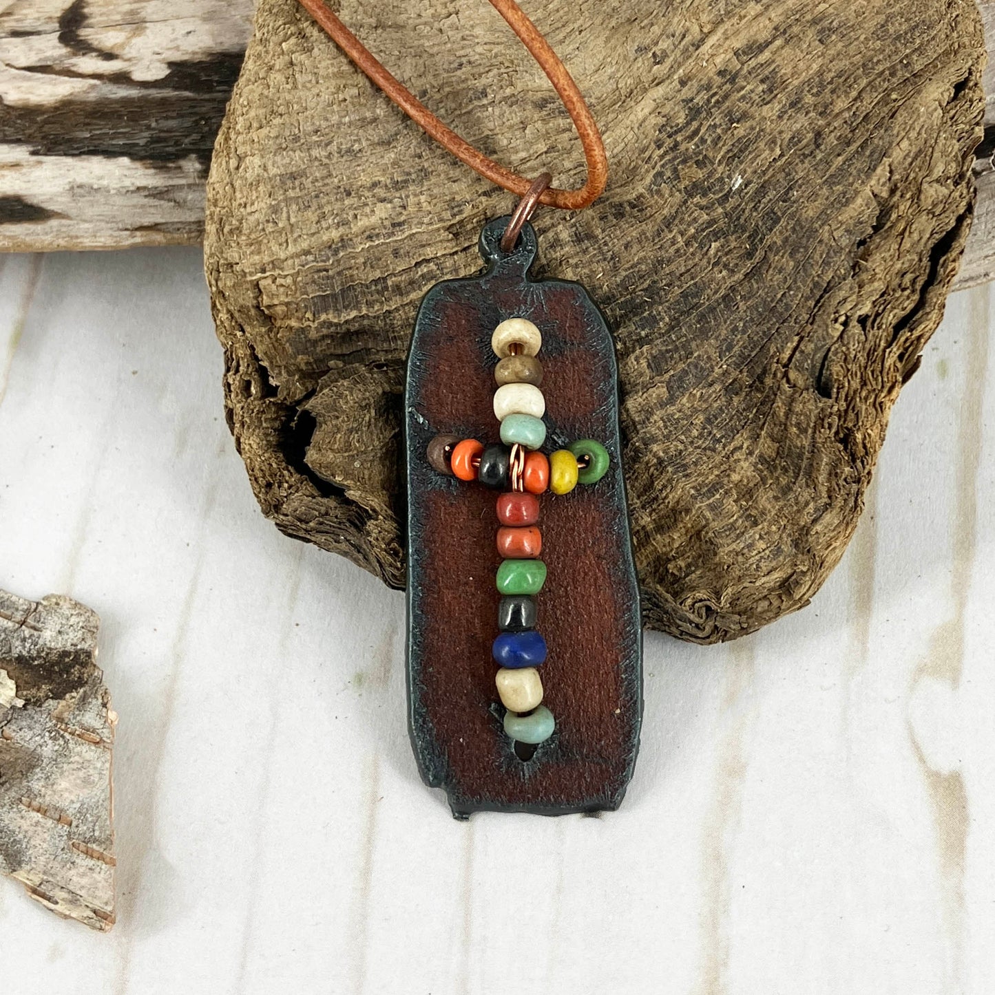 Beaded Cross necklace on aged metal base with a brown leather knoted adjustable cording by Linda Stiles Smith. For men or women.