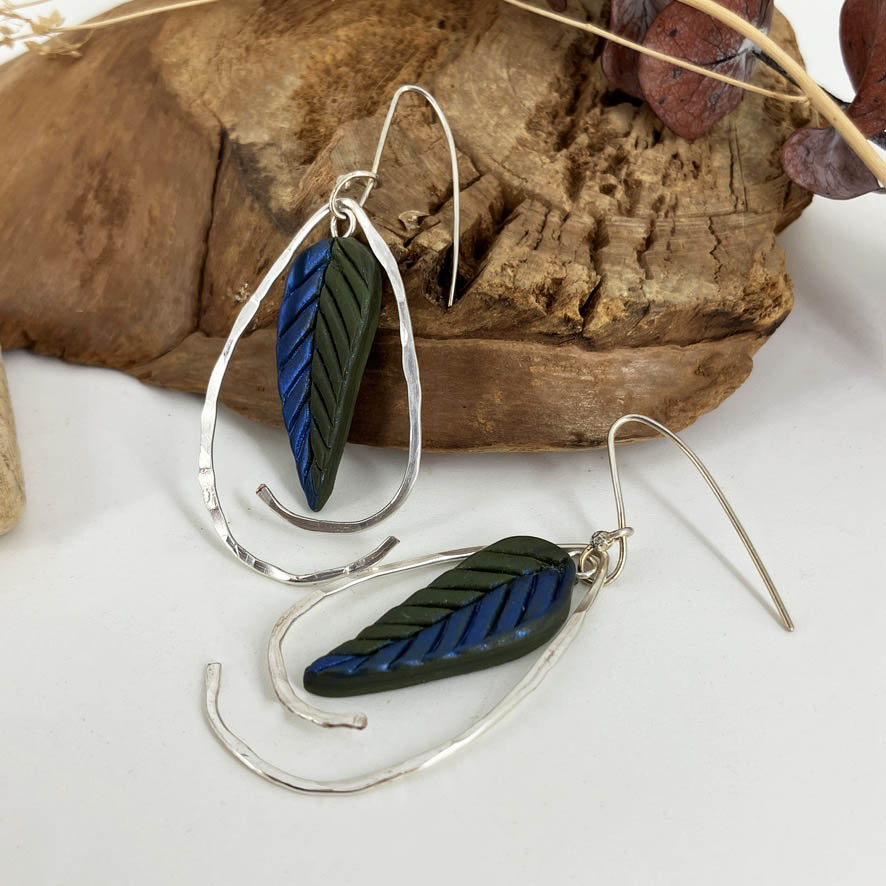 Handcrafted blue and green leaf hook earrings with a swoop of sterling silver wire framing them. Handmade sterling silver hooks.