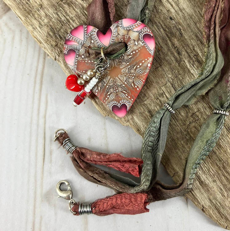 The red themed button heart pendant on sari silk is clasped by a lobster clasp for a comfortable fit.