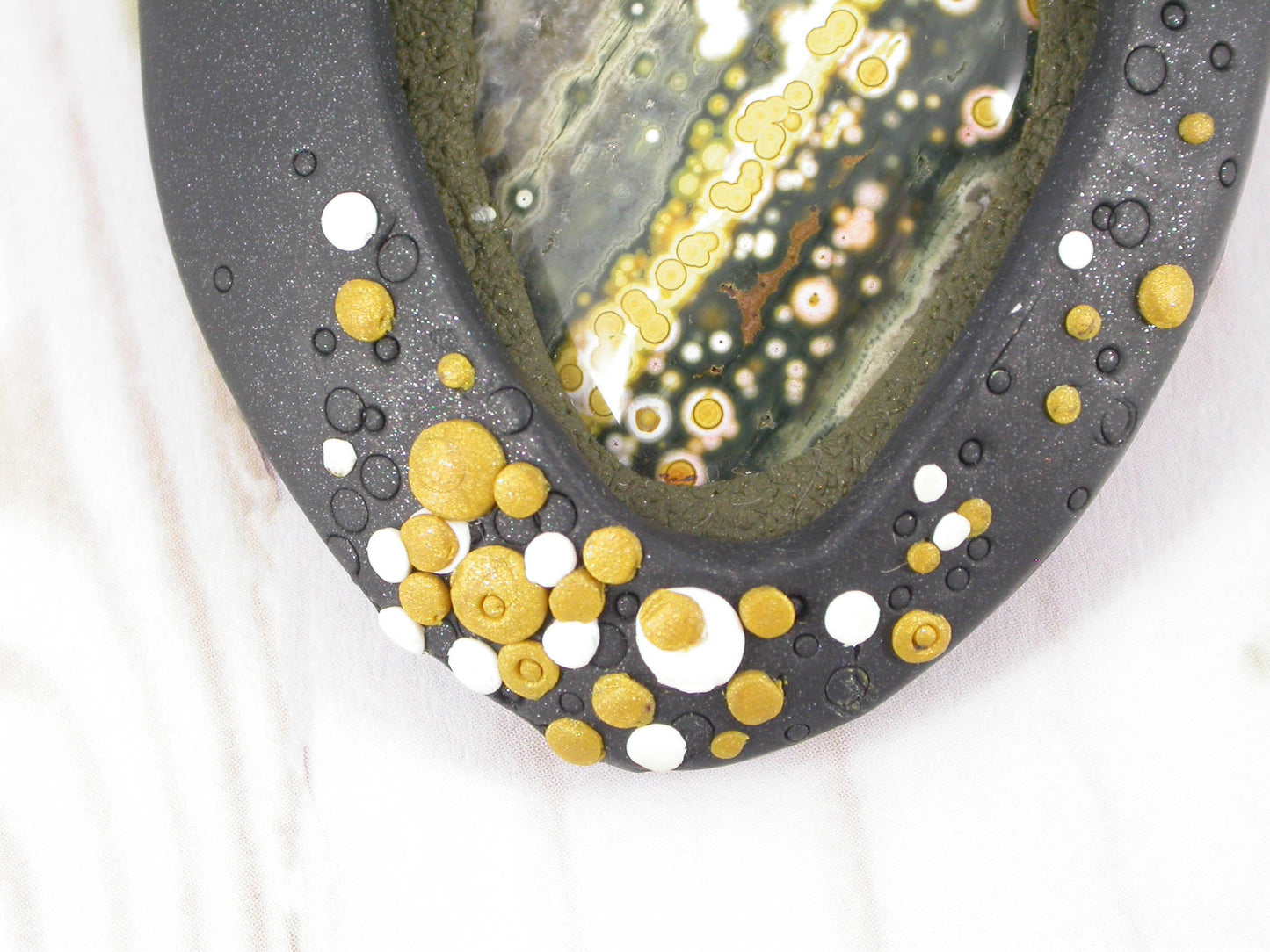 One-of-a-Kind Ocean Jasper Gemstone Brooch Handmade by Linda Stiles Smith of NatureScapes Studio. Gorgeous Ocean Green Colors, Gold Tone with White Dots and lightly sparkling Black Polymer Clay. Gift Ideas For Women. Gifts For Teachers. Wearable Art. Detailed Front View Of The Dotted End.