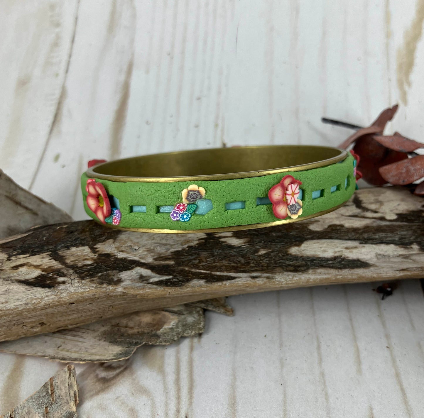 Flower bunches blossom from the green grass bangle bracelet and create a sweet accent of art jewelry to wear with your favorite spring dress! Only from NatureScapes Studio.