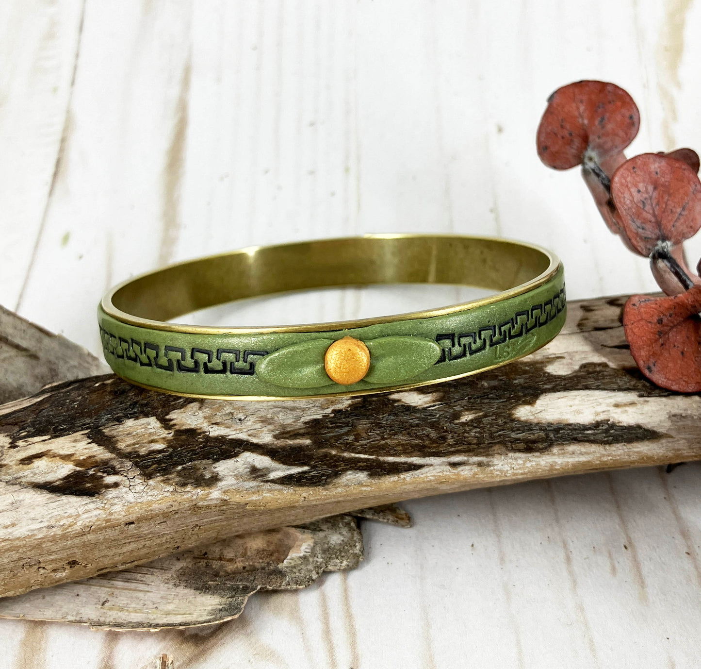 Green bangle bracelet with black squares and a leaf bow tied on by a gold dot. One of a Kind Art Jewelry piece by Linda Stiles Smith.
