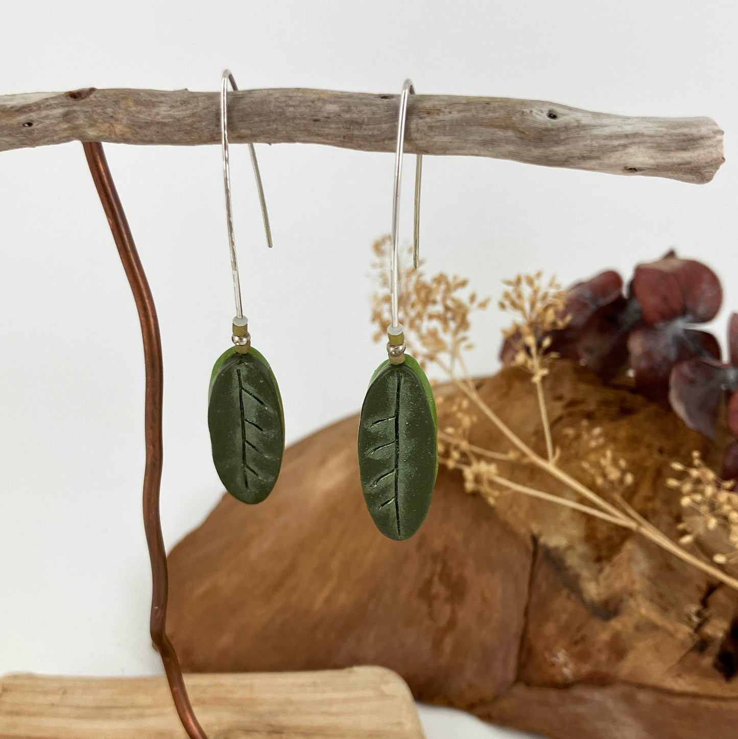 Sterling silver are long and sophisticated with a stylized green oval leaf at the end. Light green shimmers on darker green topped with tiny green beads. One of a kind jewelry for the fashionista.