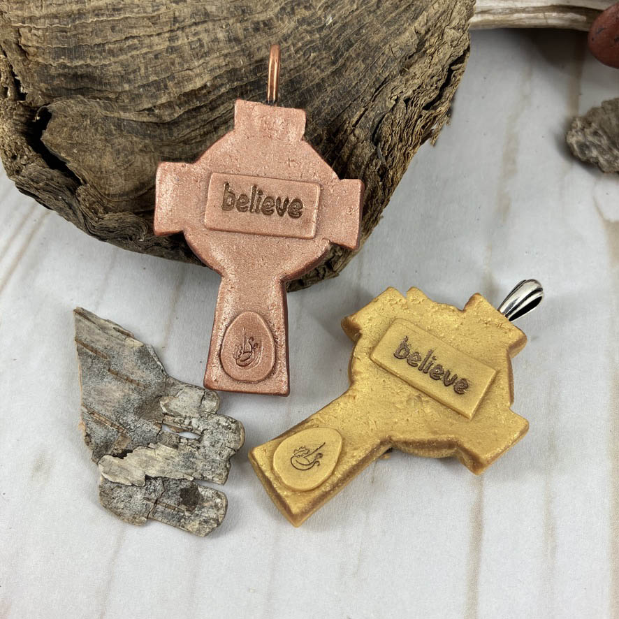 Abide in Me Medium Celtic Cross Pendant Handcrafted in Polymer Clay and genuine Swarovski Crystals by Linda Stiles Smith of NatureScapes Studio. Back View of the Bronze clay color and the Gold clay color stamped with the word Believe. Christian Gifts For Women.
