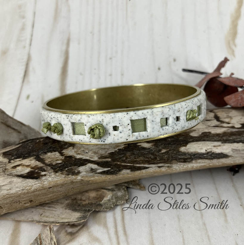 Green spouts peek thru holes of the double layered bangle bracelet. Designed by Linda Stiles Smith