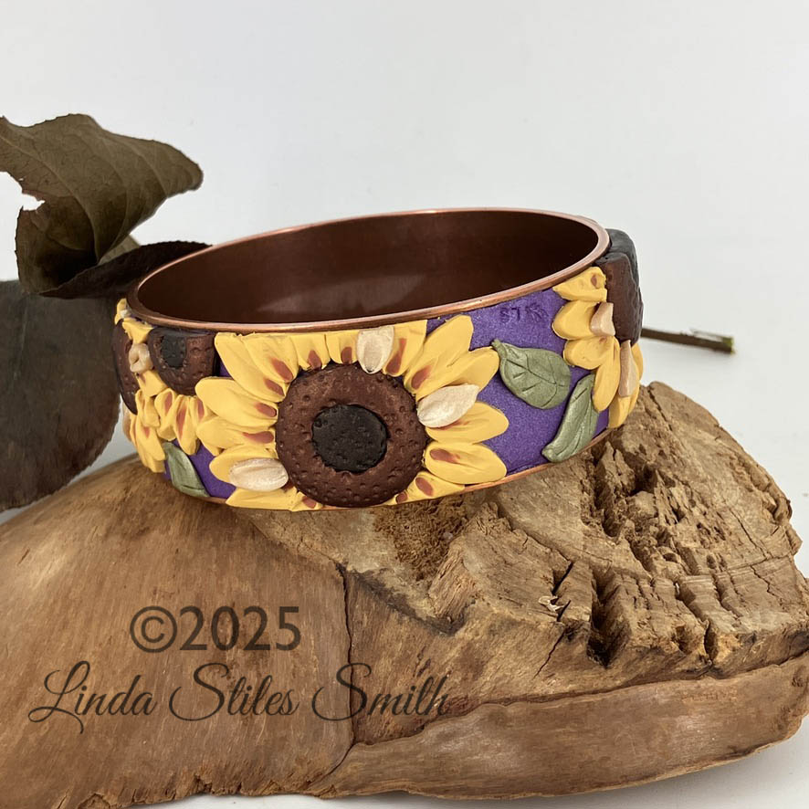 Sunflower adorned bangle bracelet by Linda Stiles Smith is bright and sunny yellow on purple on a copper base.