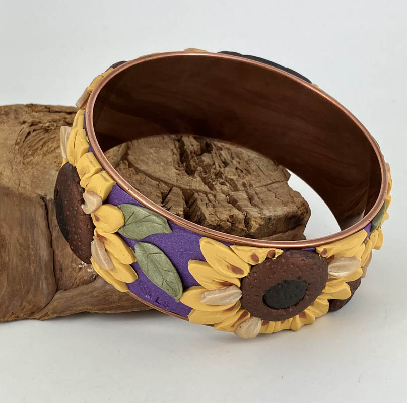 The copper base securely holds the sunflower motif surrounding this wide bangle bracelet. Handcrafted by Linda Stiles Smith of Naturescapes Studio.
