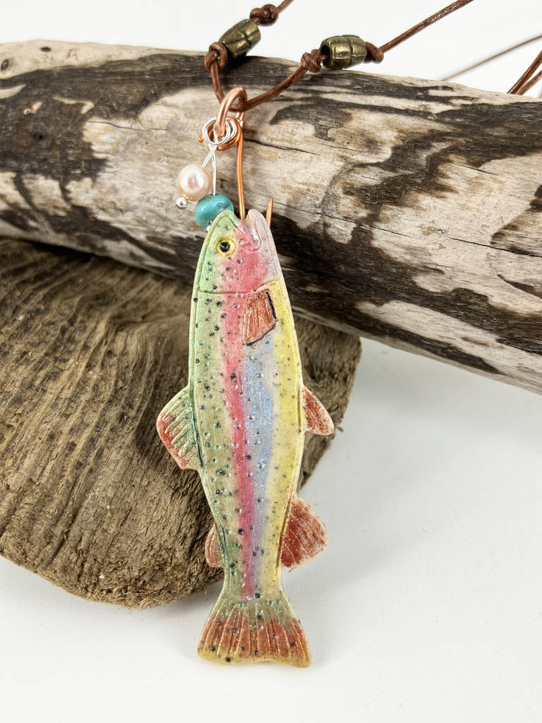 Rainbow Trout painted with shimmering powders handing from a copper hook with pearl "bubbles" on a leather cord makes a statement necklace. By Linda Stiles Smith