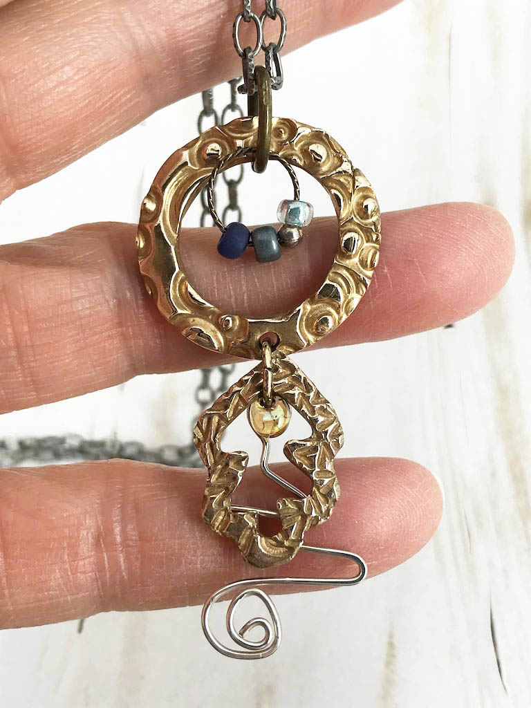 Handmade one of a kind bronze metal clay necklace paired with a touch of sterling silver, coordinated blue beads and brass, plus a steel necklace chain. The perfect gift for a unique woman. Designed by Linda Stiles Smith of NatureScapes Studio. Front view.