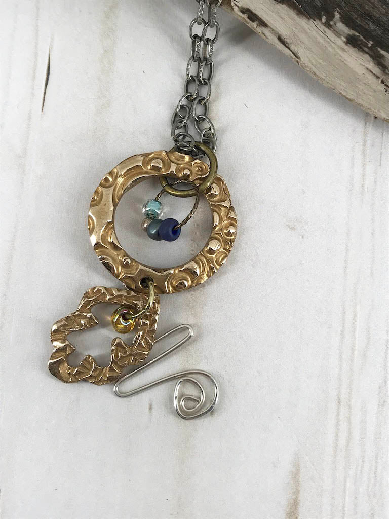Handmade one of a kind bronze metal clay necklace paired with a touch of sterling silver, coordinated blue beads and brass, plus a steel necklace chain. The perfect gift for a unique woman. Designed by Linda Stiles Smith of NatureScapes Studio. Front view.
