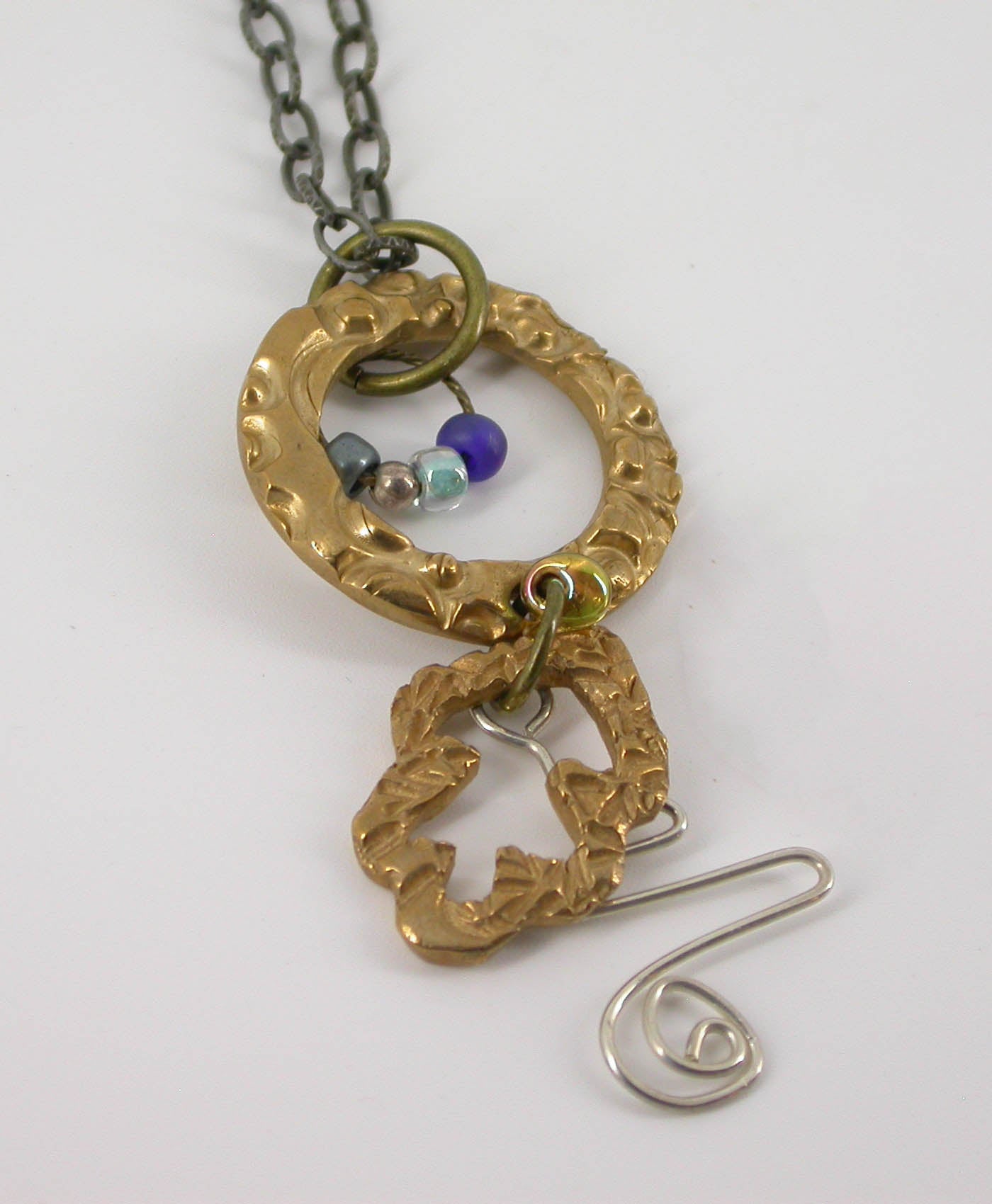 Handmade one of a kind bronze metal clay necklace paired with a touch of sterling silver, coordinated blue beads and brass, plus a steel necklace chain. The perfect gift for a unique woman. Designed by Linda Stiles Smith of NatureScapes Studio. Front view.