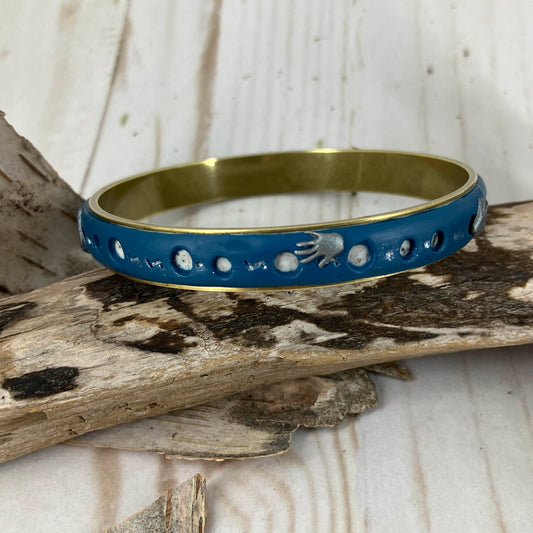 Cobalt blue bangle bracelet in polymer clay layered on brass with tiny silver hands. Dotted with round holes that reveal grey granite clay beneath. Handcrafted by Linda Stiles Smith.