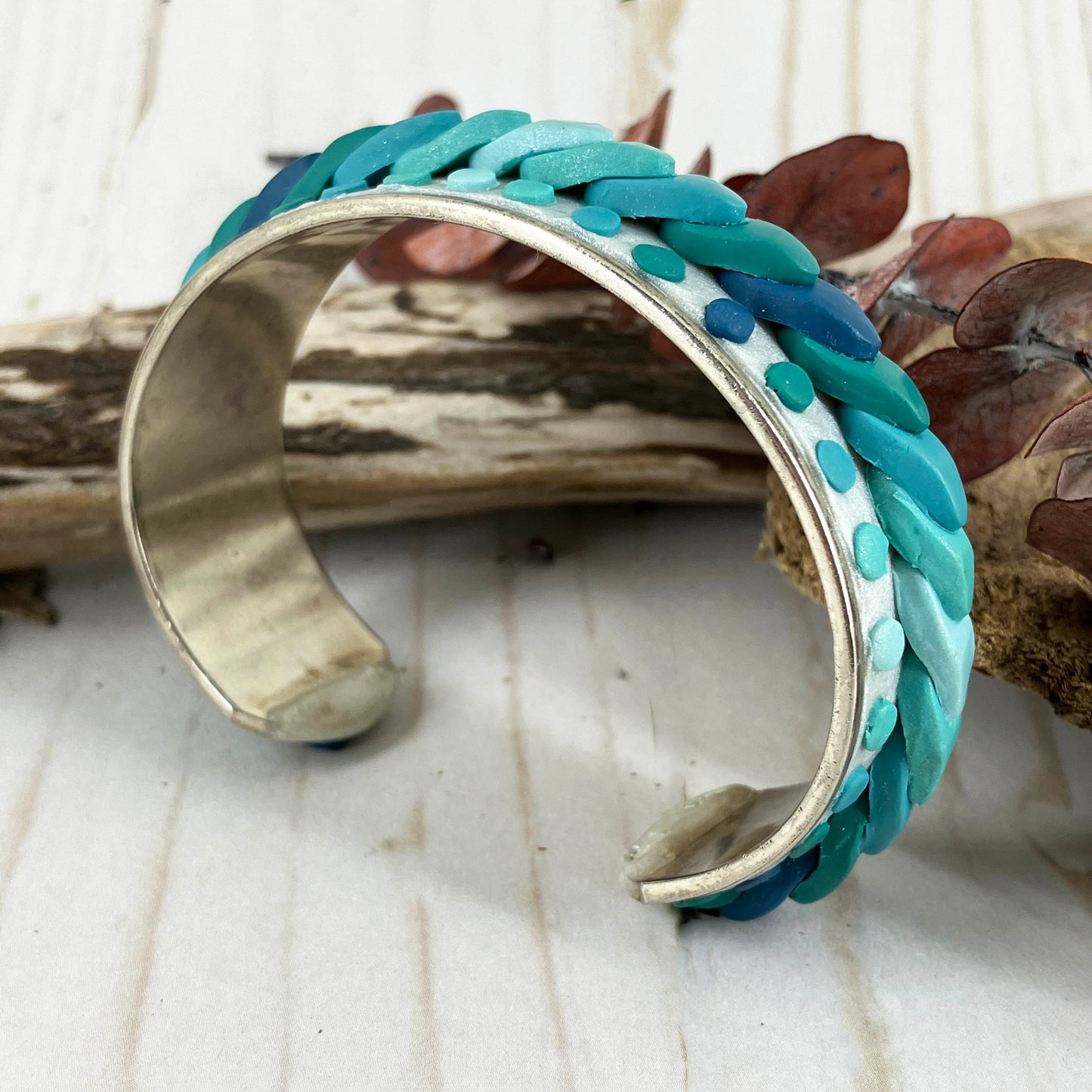 Sitting on a solid base of silver plated the waves of color stream across the top of this cuff bracelet. Accented by turquoise, blue and green dots the colors flow from one end to the other. Great for vacationing even at home! Handmade for water loving women on any coast by Linda Stiles Smith