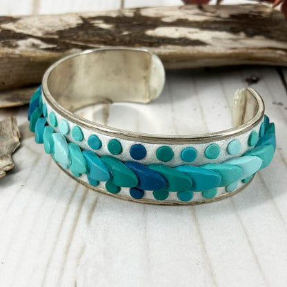 Watch the waves come in on this silver metal cuff bracelet covered with turquoise and blue polymer clay waves. Dots emerge from the white waters to follow them along the circumference. Designed one of a kind wearable art by Linda Stiles Smith.