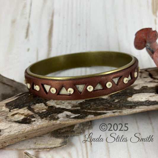 Metallic brown with triangle holes revealing ivory granite inside of this bangle bracelet. Dots dance between each triangle accenting the colors and shapes. Handcrafted by Linda Stiles Smith