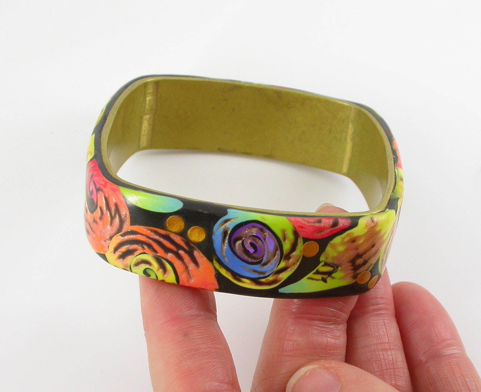 Colorful Swirls Synphony Bangle Bracelet handmade with Polymer Clay by Linda Stiles Smith of NatureScapes Studio. Side view in hand. Gift ideas for women who like unique jewelry.