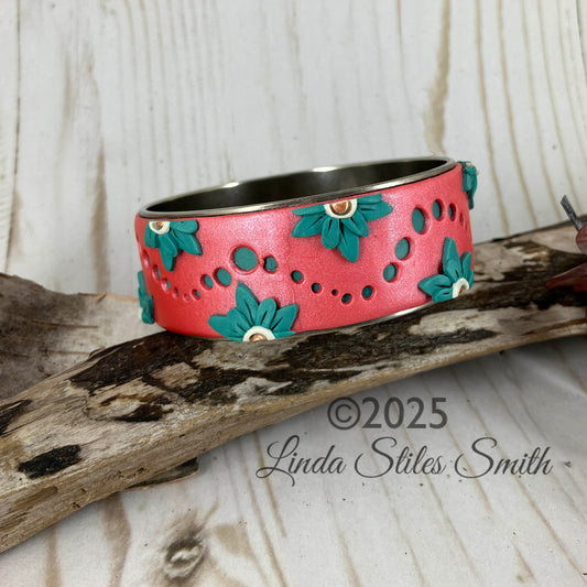 Turquoise dots flow on a coral sunset bangle bracelet accented by turquoise half flowers. Handcrafted by Linda Stiles Smith