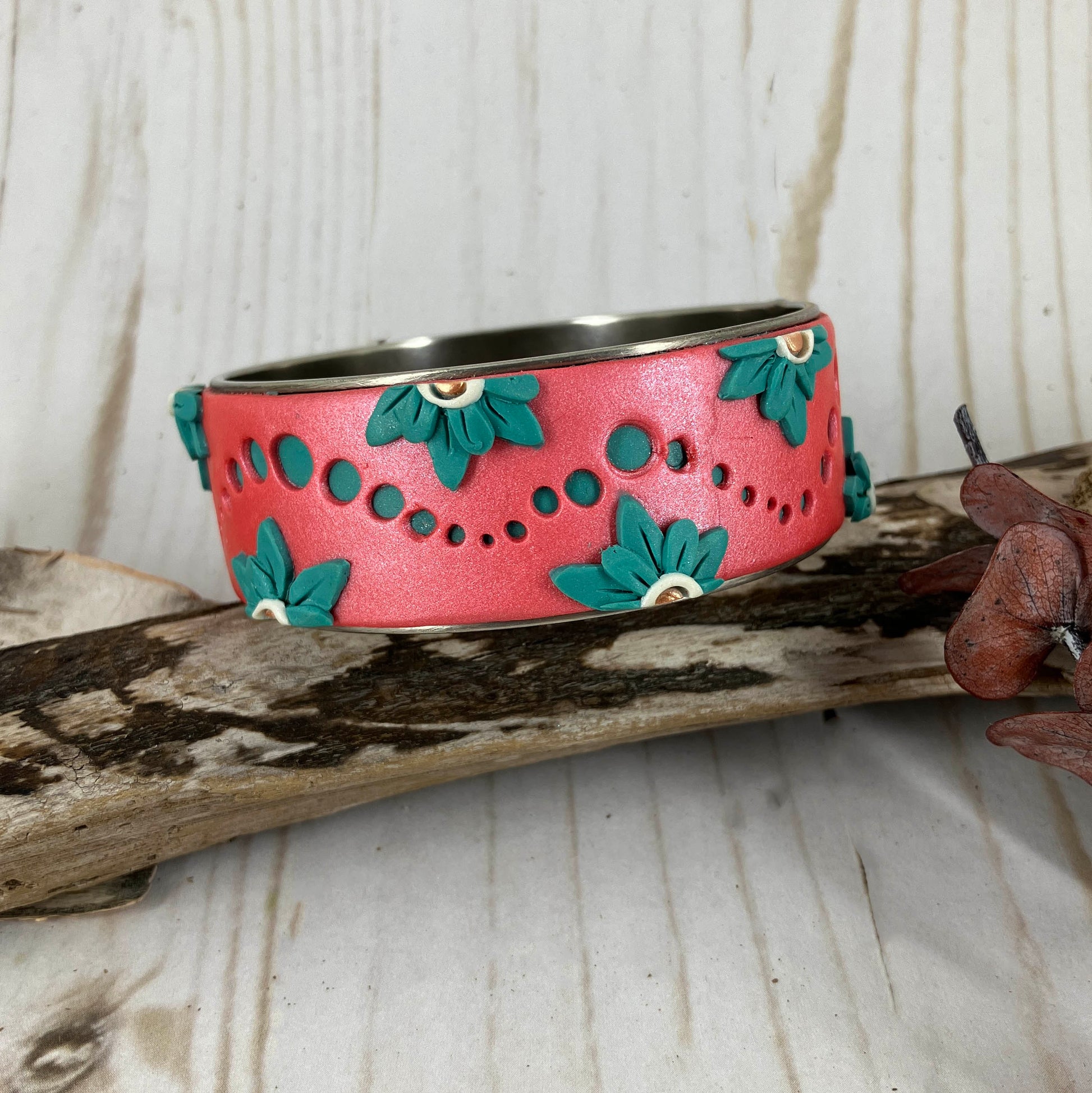 Rolling waves of turquoise in the form of dots on the sunset coral surface is adorned with turquoise flowers along the edges. This one of kind bangle bracelet is handcrafted by Linda Stiles Smith of NatureScapes Studio.