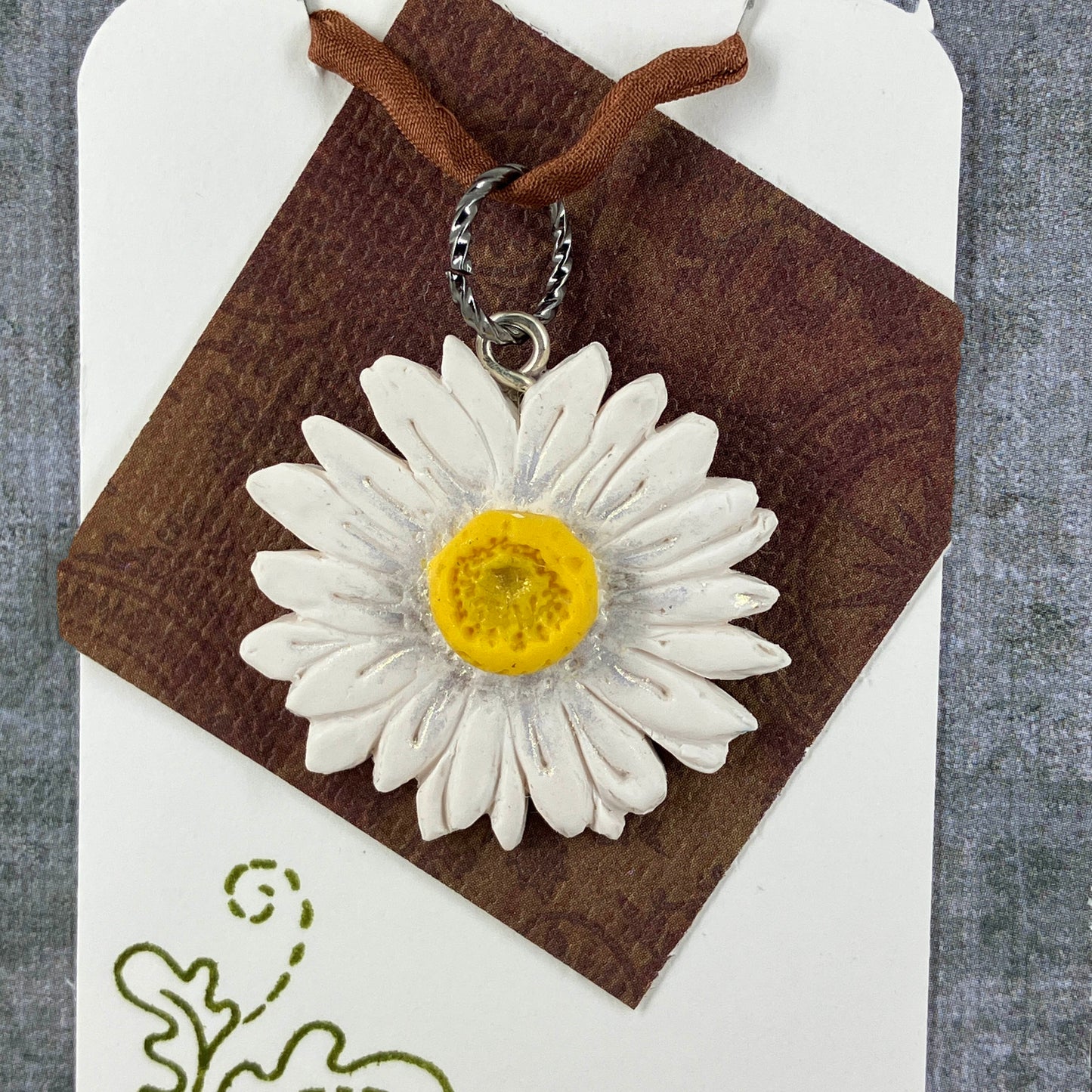 Polymer Clay White Daisy pendant accented in sparkling gold mica powder on a ring for a joyful spring outfit. Handcrafted by Linda Stiles Smith