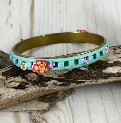 Sweet little flowers up and down the blue and green cut out bangle bracelet is a whimsical design by Linda Stiles Smith of NatureScapes Studio.