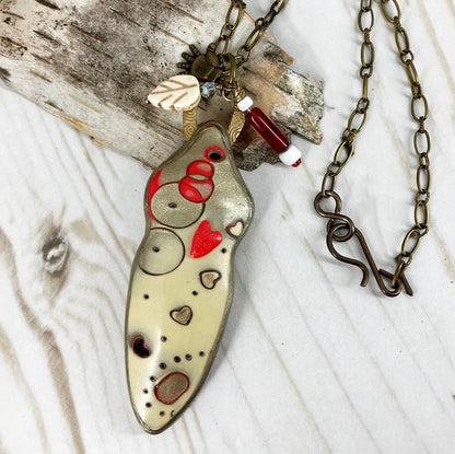 One of a kind handmade polymer clay statement necklace features hearts on a figure shape. Red and gold and bronze for valentines day makes a special gift. Original design by Linda Stiles Smith of NatureScapes Studio.