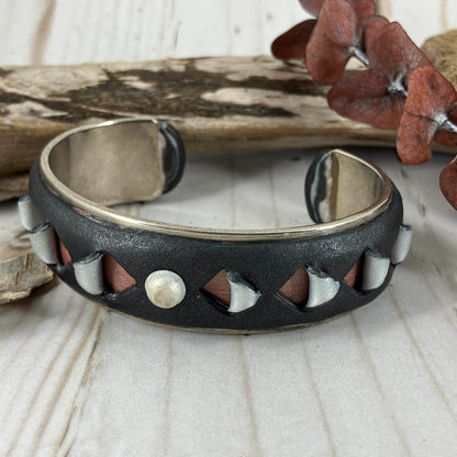 Black cuff braclet with carved back shapes of color in polymer clay on silver base. Hand crafted one of a kind by Linda Stiles Smith.