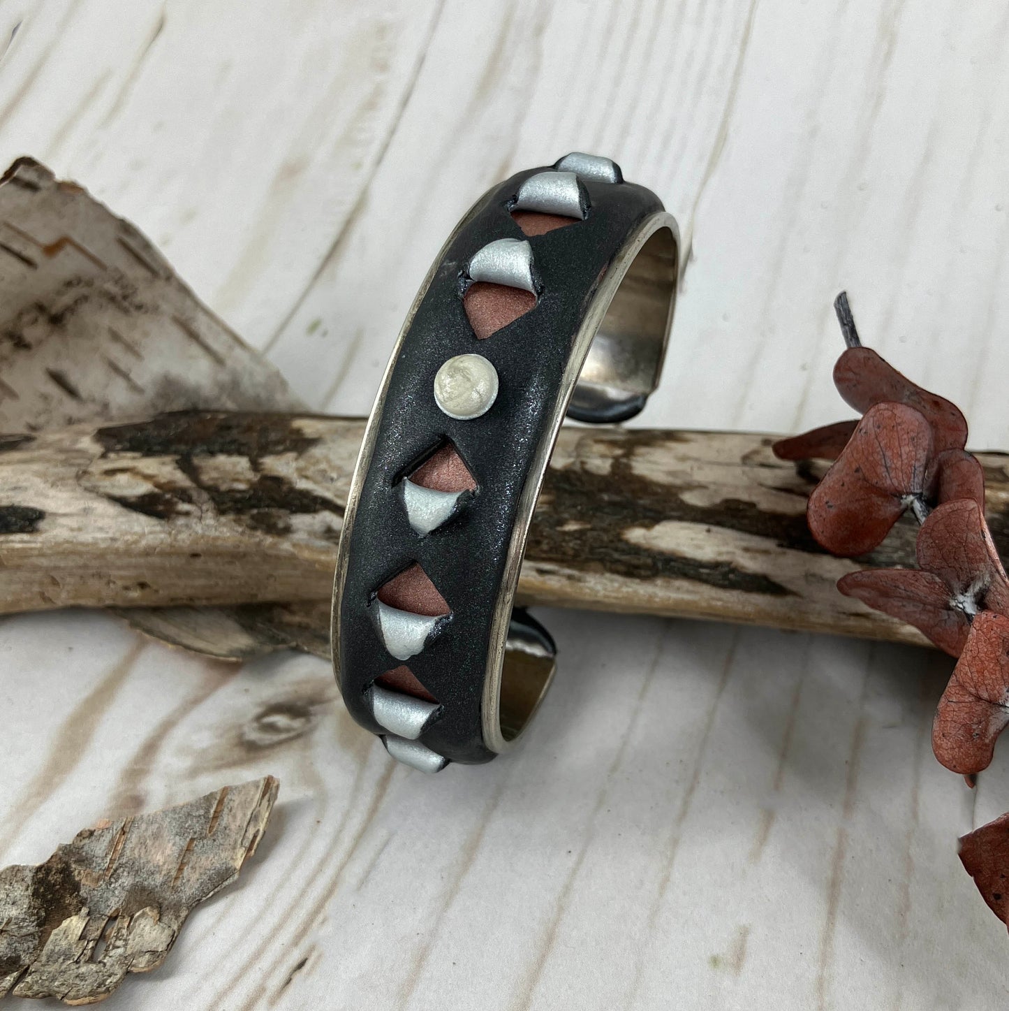 Cut out detail of black cuff bracelet with triangle peek-a-boo design on silver. Handcrafted by Linda Stiles Smith