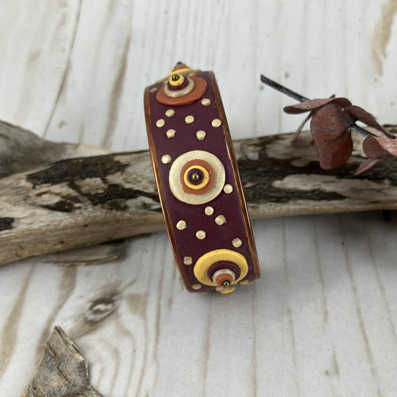 both large and small dots  of pearl, copper, yellow and red cover the entire surface of the deep red cuff 