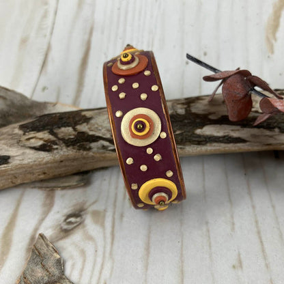 both large and small dots  of pearl, copper, yellow and red cover the entire surface of the deep red cuff 