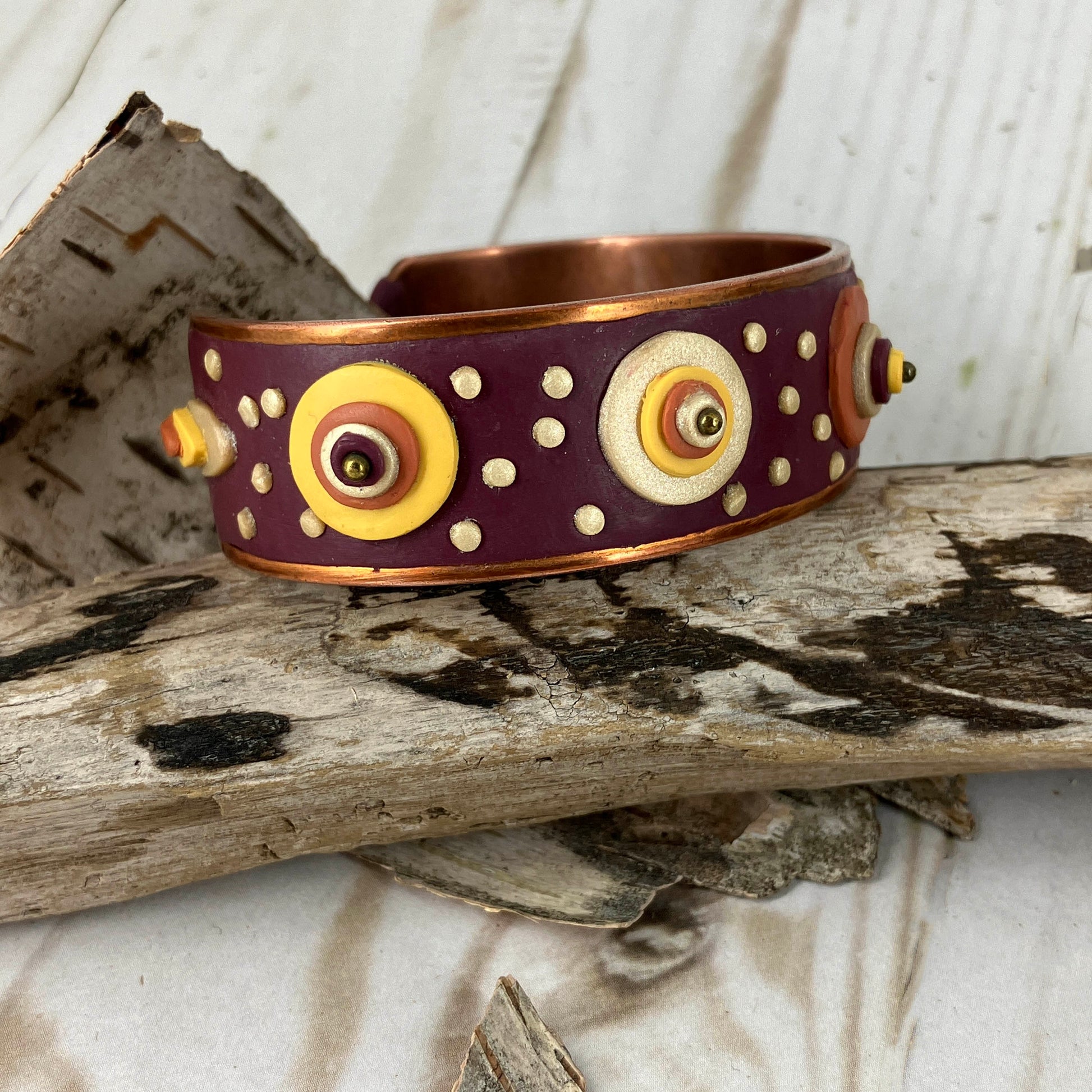 copper cuff bracelet with dots of colorful clay all over the surface stacked in different sizes