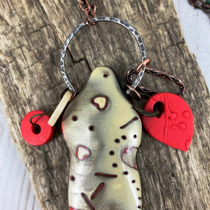 Close up of Symbol of Love Pendant with ring and red polymer clay charms dangling on top. One of a kind necklace by Linda Stiles Smith. 