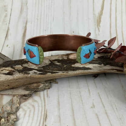 Ends of cuff bracelet in blue with triangle cutouts pealed back. Copper base with green ends. Handmade by Linda Stiles Smith.