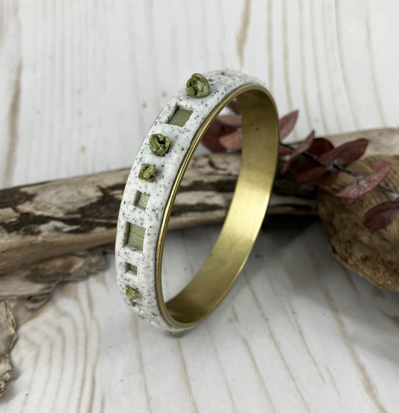 Brass bangle covered in leaf green and white granite clay reveals squares of green and pops of green leaf clusters all around. Handcrafted by Linda Stiles Smith