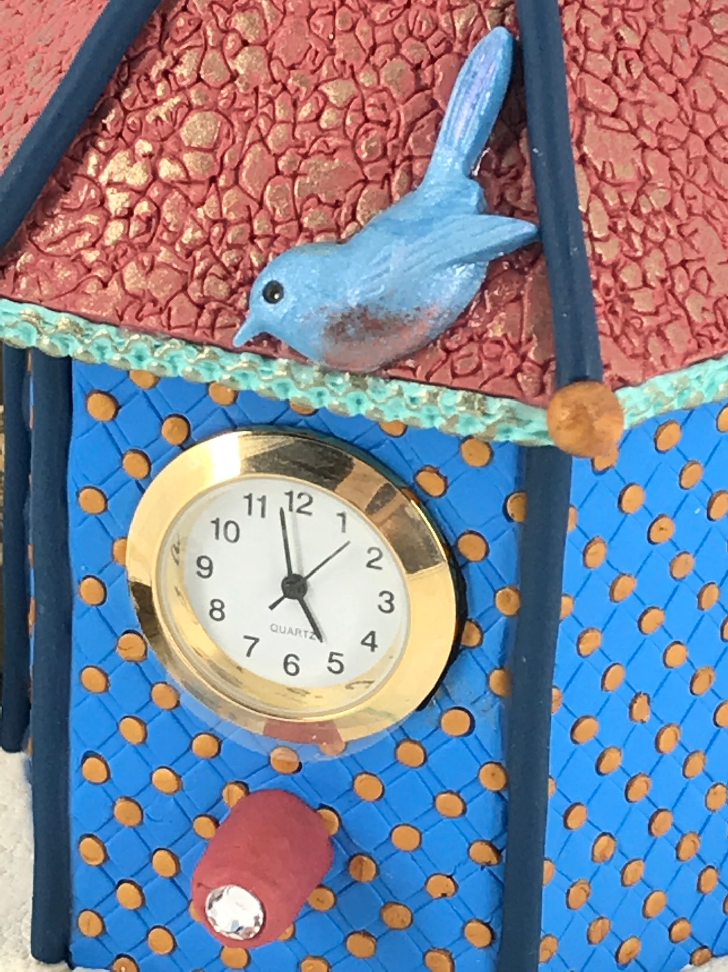 Small blue dot on shelf bird house clock handmade with Polymer Clay by Linda Stiles Smith of NatureScapes Studio. Close up of the front view with a blue bird. Gift for women ideas.