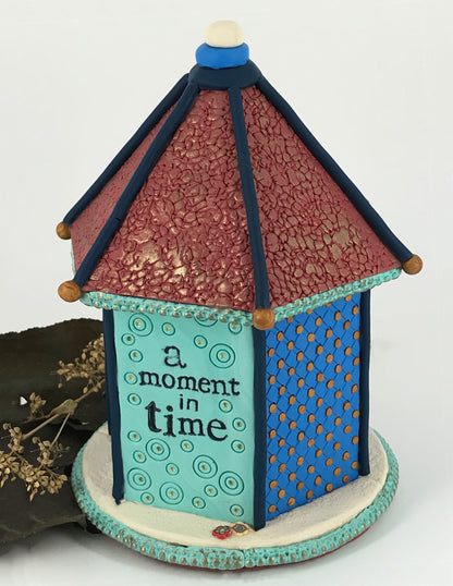 Small blue dot on shelf bird house clock handmade with Polymer Clay by Linda Stiles Smith of NatureScapes Studio. Back View stamped with the words "a moment in time". Gift for women ideas.